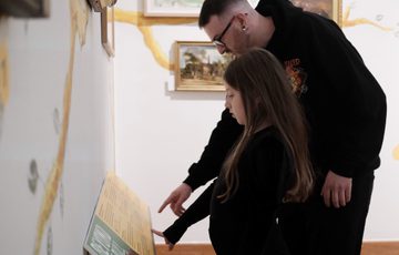 An adult and child looking at object labels on display.