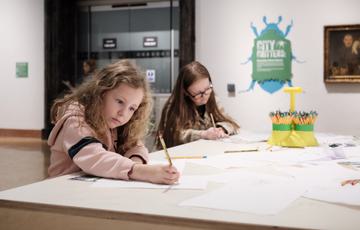 Two children sitting at a desk and drawing.