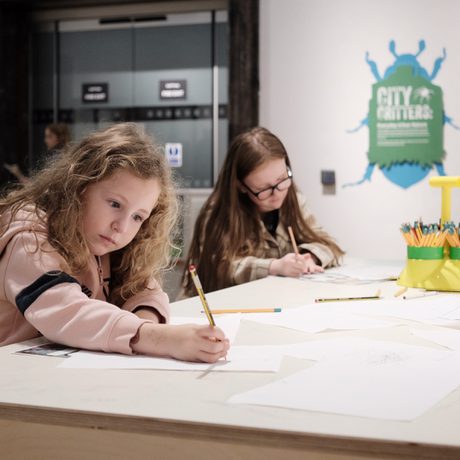 Two children sitting at a desk and drawing.