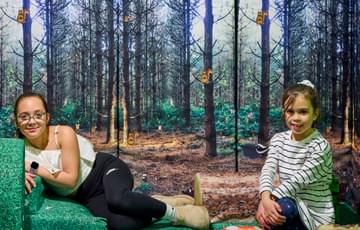 A small soft play area with two children and woodland graphic behind.