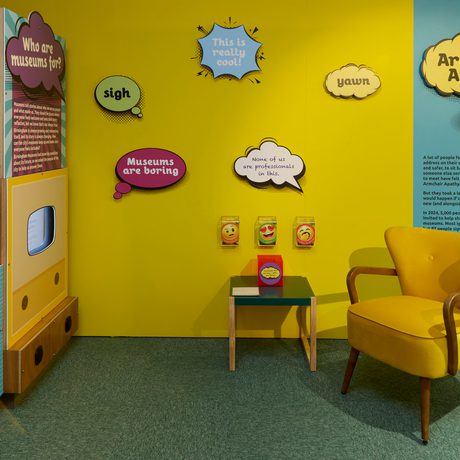 A gallery display area featuring yellow chair and colourful speech bubbles on the wall.
