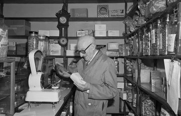 Black and white photo of a shop keeper in a sweet shop.