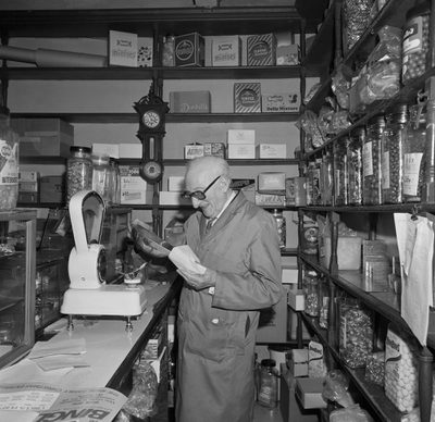 Black and white photo of a shop keeper in a sweet shop.