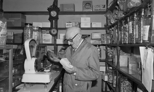 Black and white photo of a shop keeper in a sweet shop.