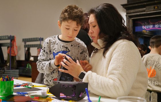An adult and child taking part in a craft activity at a table.