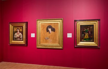 Three Pre-Raphaelite paintings in gold frames on a red wall.