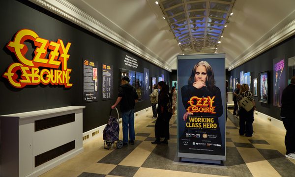 Ozzy Osbourne exhibition with large 'Ozzy Osbourne' graphic, black walls and people in the exhibition space.