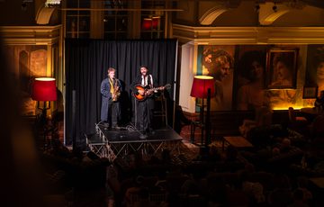 Two musicians performing on stage with saxophone and guitar.