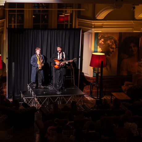 Two musicians performing on stage with saxophone and guitar.