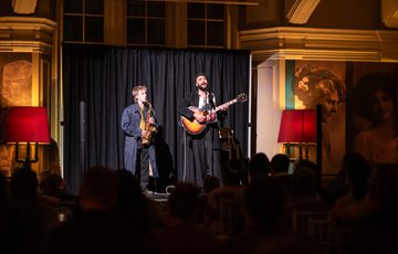 Two musicians performing on stage with saxophone and guitar.