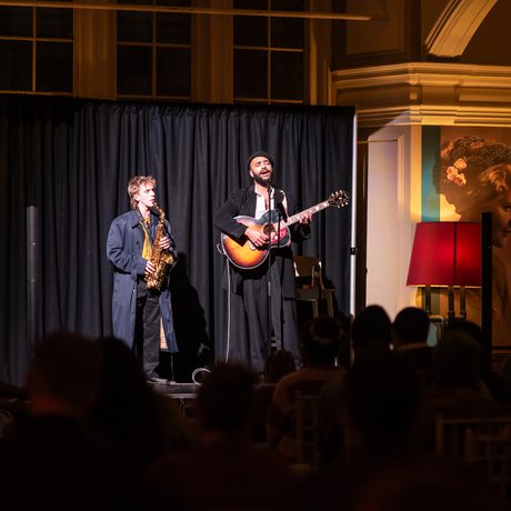 Two musicians performing on stage with saxophone and guitar.