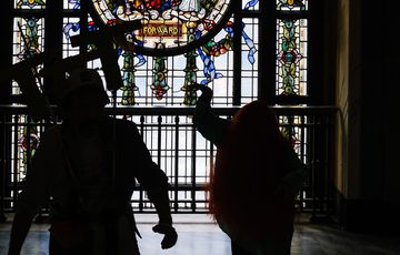Silhouetted figures pose in front of an ornate stained glass window displaying "FORWARD."