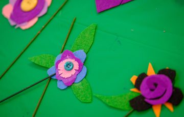 An adult and young girl happily crafting with colourful paper and scissors.