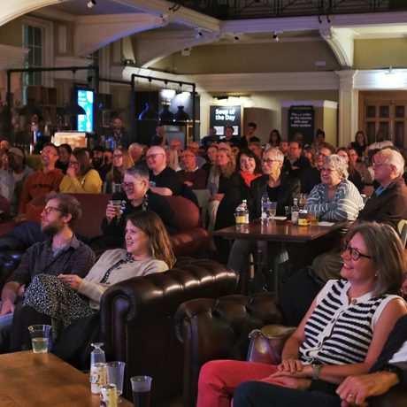 Audience attentively watching a performance or presentation in a cozy, dimly lit venue.