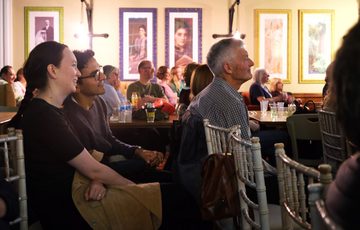 People attentively watching a performance in a warmly lit room.