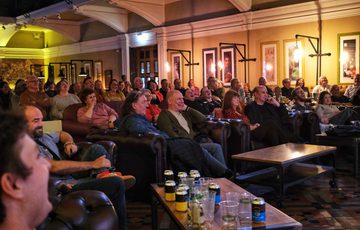 Audience enjoying a comedy show or live performance in a cozy, warmly lit venue.
