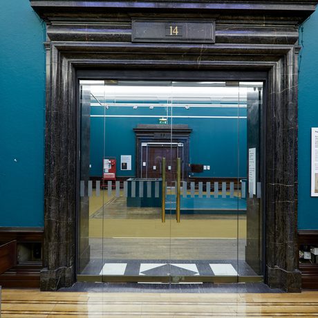 A ornate black doorway with glazed doors leading onto another gallery.
