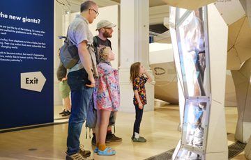 A family looking at a part of the life-sized 3D model with fossilised leg bone on display.