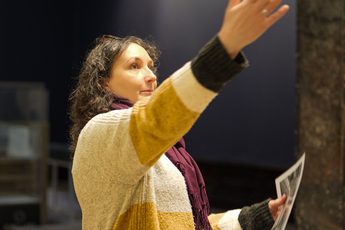 A staff member pointing up in the air to something out of the shot.