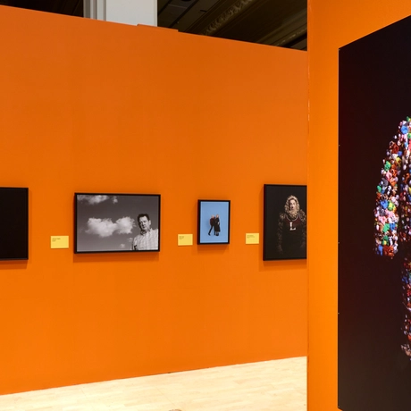 Gallery wall with four framed photos and one large photo of Joe Lycett in colourful teddy bear outfit.