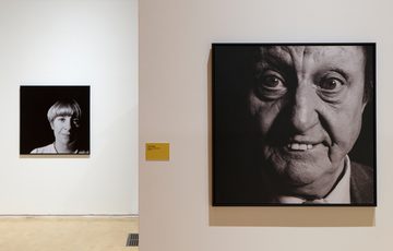 Two black-and-white close-up portrait photographs of comedians Victoria Wood and Ken Dodd displayed in an art gallery.
