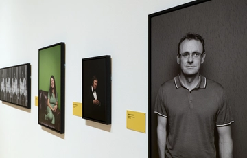 A gallery wall featuring various portrait photographs of comedians.