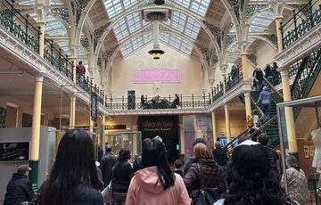 Lots of people in a gallery looking at a string quartet playing on the balcony above.