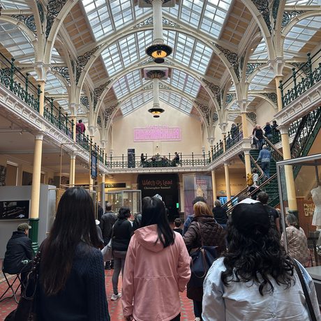 Lots of people in a gallery looking at a string quartet playing on the balcony above.