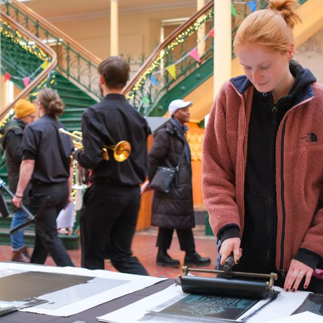 A person uses roller on a print in printmaking workshop.