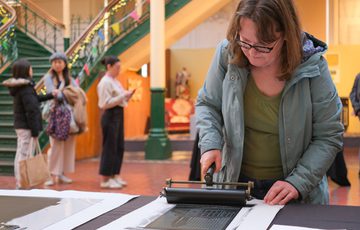 A person uses a roller to print on sheet.