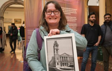 A smiling person holding detailed black-and-white architectural print.