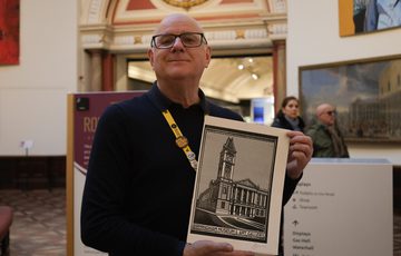 A person proudly holds detailed print inside an art gallery.