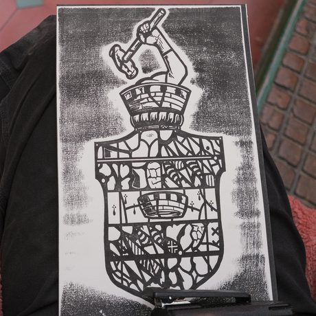 Hand holding a black-and-white print of a detailed shield.