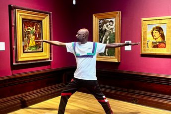 A person doing yoga in an art gallery - paintings in gold frames are on the walls.