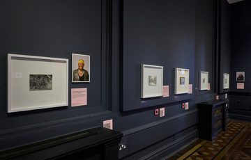 Row of drawings and photographic portraits on display.