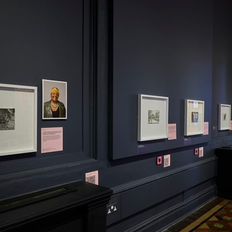 Row of drawings and photographic portraits on display.