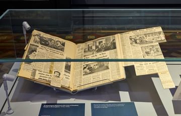 A book of newspaper clippings on display.