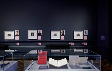 Display cases and portrait photos and drawings beyond.