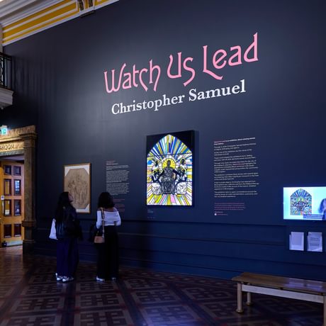 Display wall with people looking at the stained glass artwork.