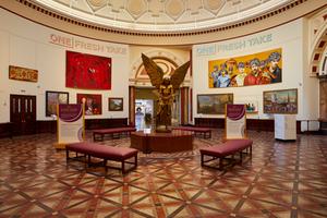 A view of the Round Room with large painting on the wall and a statue of Lucifer by Sir Jacob Epstein.