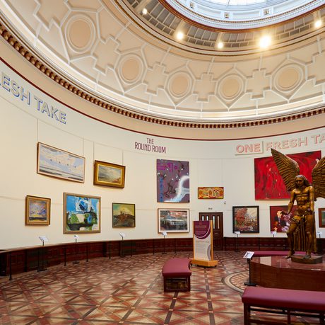 A view of half of the Round Room with large painting on the wall and a statue of Lucifer by Sir Jacob Epstein.