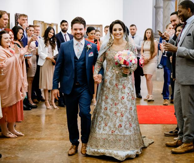 A newly married couple walking surrounded by their friends and family