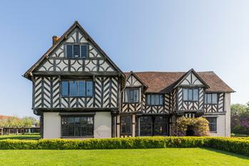 Exterior front view of a Tudor timber-framed house and garden