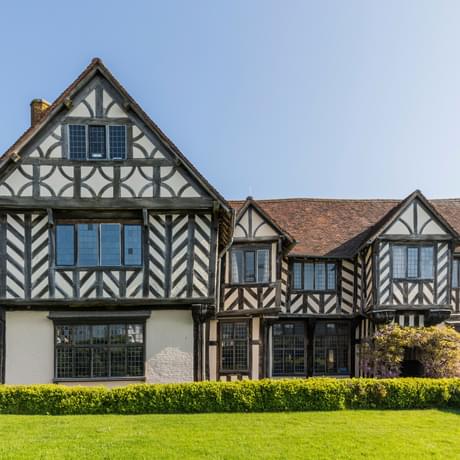 Exterior front view of a Tudor timber-framed house and garden