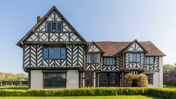 Exterior front view of a Tudor timber-framed house and garden