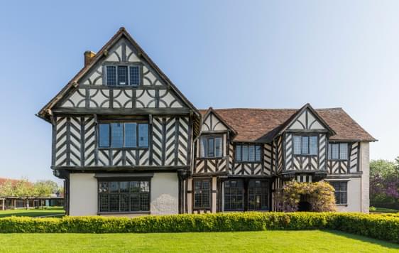 Exterior front view of a Tudor timber-framed house and garden