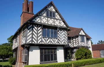 Exterior front view of a Tudor timber-framed house and garden.