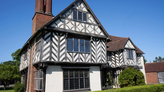 Exterior front view of a Tudor timber-framed house and garden.