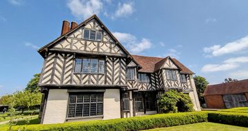 Exterior front view of a Tudor timber-framed house and garden.