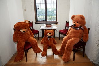 The three large teddy bears sitting on chairs.